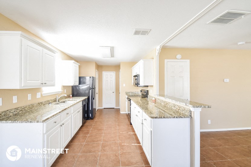 a large kitchen with white cabinets and granite counter tops