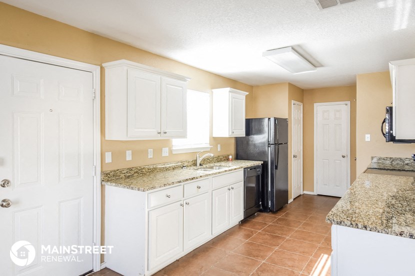 a kitchen with white cabinets and a black refrigerator