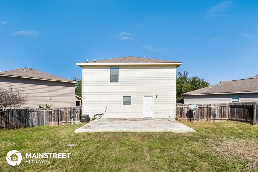 a small white house with a yard and a basketball hoop