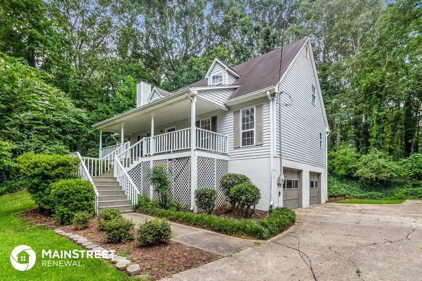 a small white house with a porch and a driveway