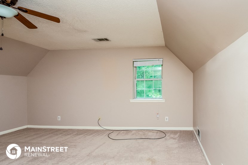 the living room of a home with a ceiling fan and a carpet
