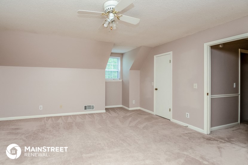 the bedroom of this home is empty and has a ceiling fan