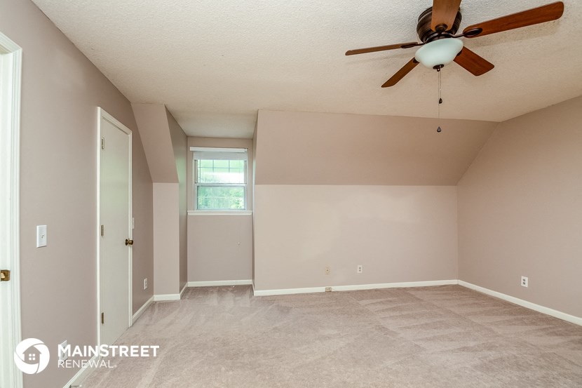 the spacious living room with carpet and a ceiling fan