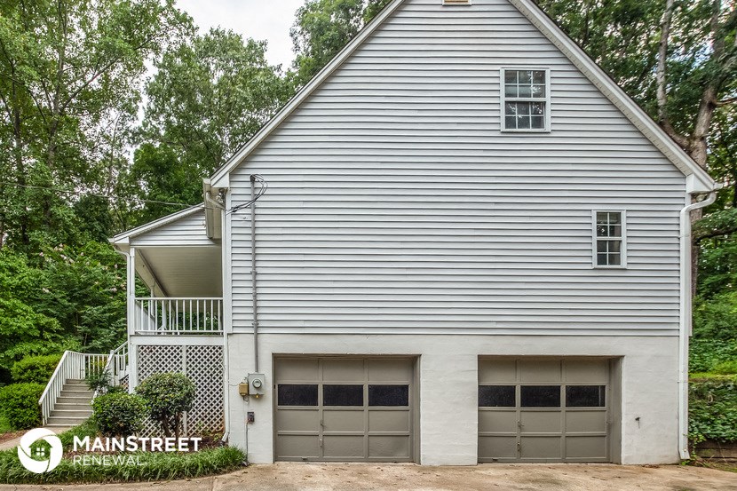 the side of a white house with two garage doors