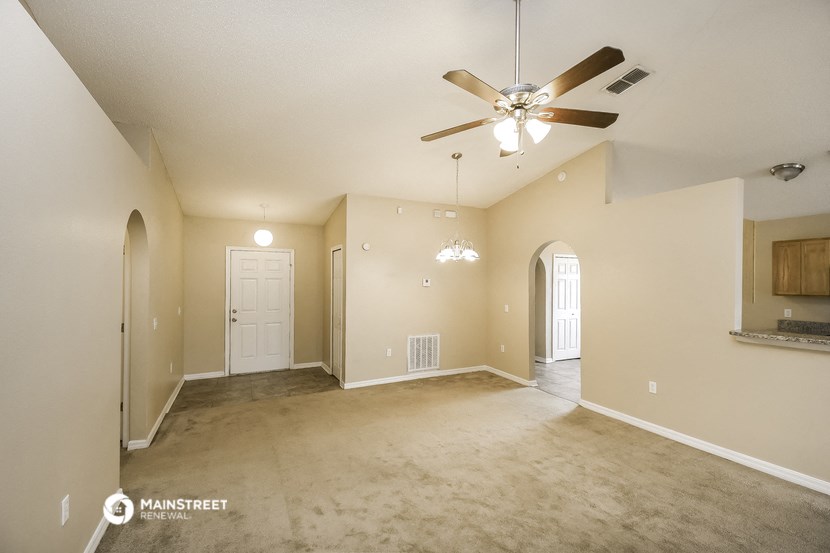 an empty living room with a ceiling fan