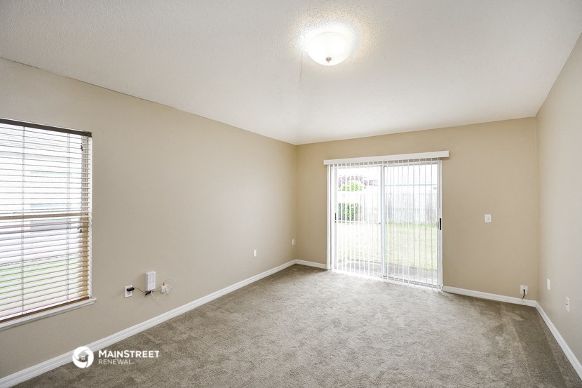 the spacious living room with a large window and carpeting
