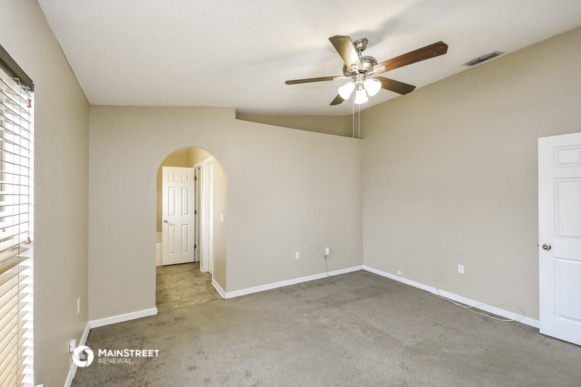 the spacious living room with ceiling fan and carpeting