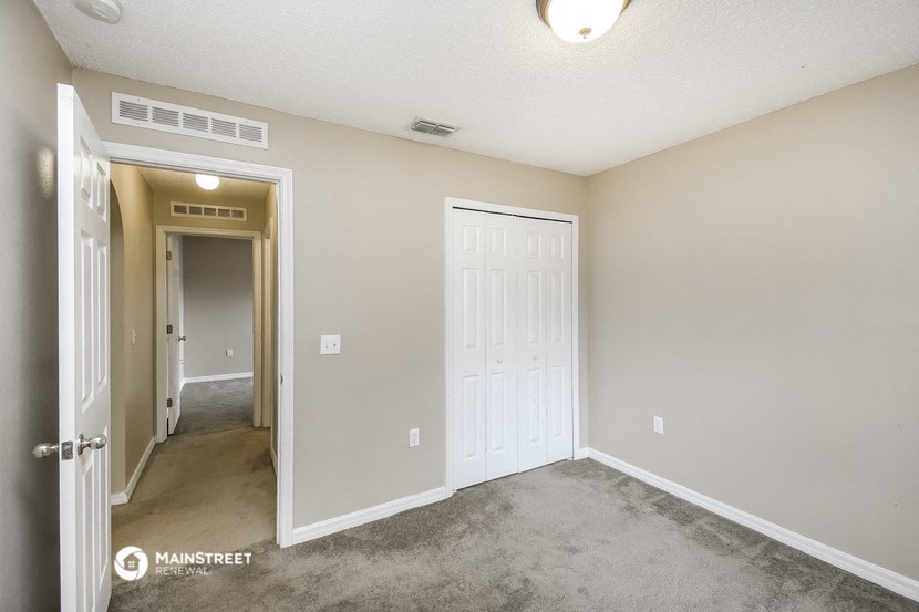 a bedroom with a carpeted floor and a door to a hallway