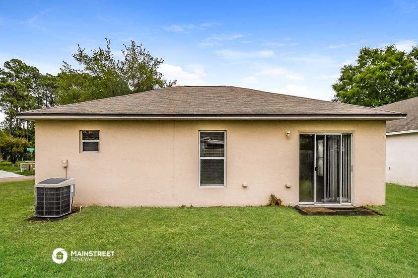 a cream colored house with a yard and a trash can