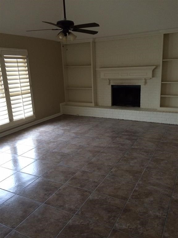 an empty living room with a fireplace and a ceiling fan