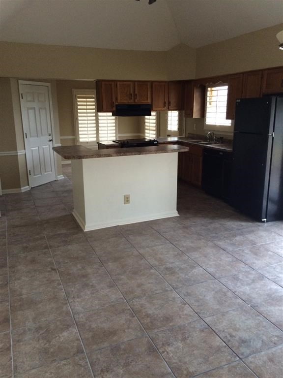 an empty kitchen with a refrigerator and a sink