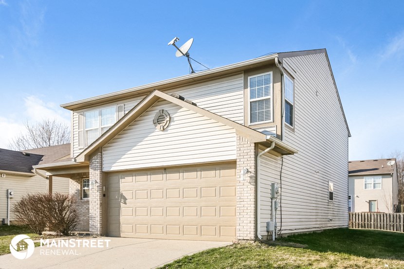 a white house with a garage and a wind turbine on top of it