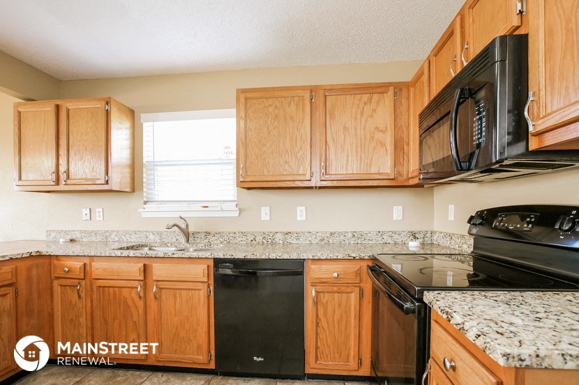 a kitchen with wood cabinets and black appliances and granite counter tops