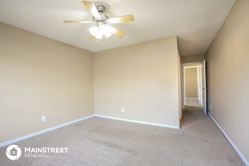 the spacious living room with carpet and ceiling fan