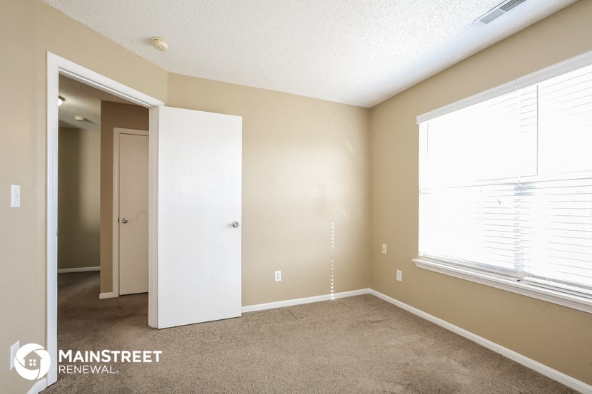 a bedroom with a carpeted floor and a large window