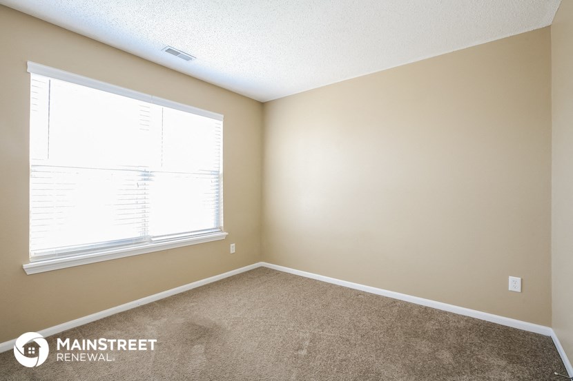 a bedroom with a carpeted floor and a large window