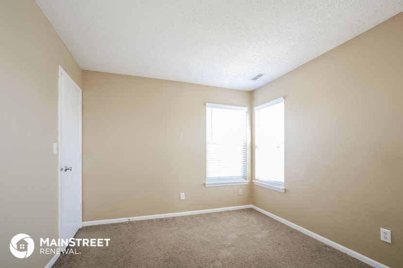 a bedroom with a carpeted floor and two windows