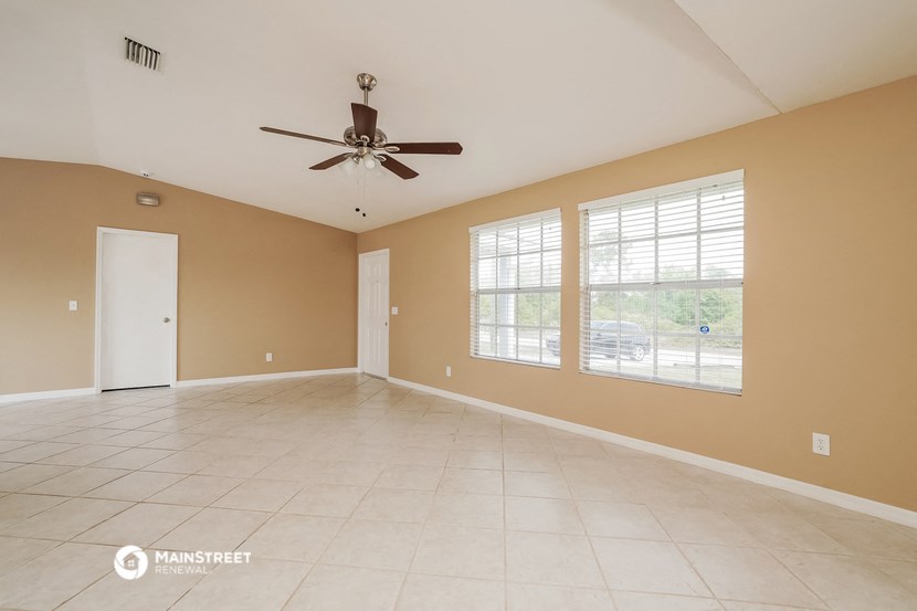 an empty living room with a ceiling fan and a large window