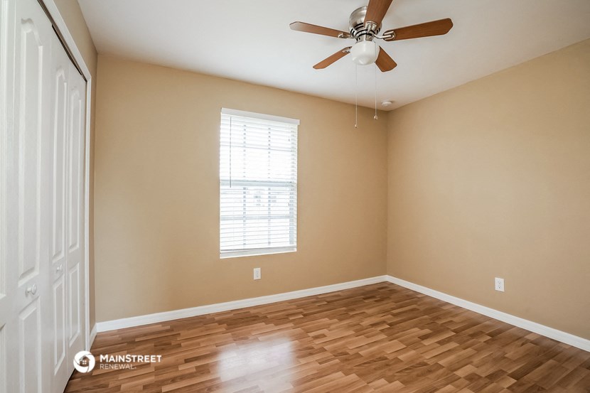 the spacious living room with hardwood floors and a ceiling fan