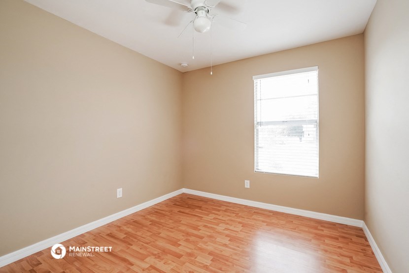 the spacious living room with wood flooring and a window