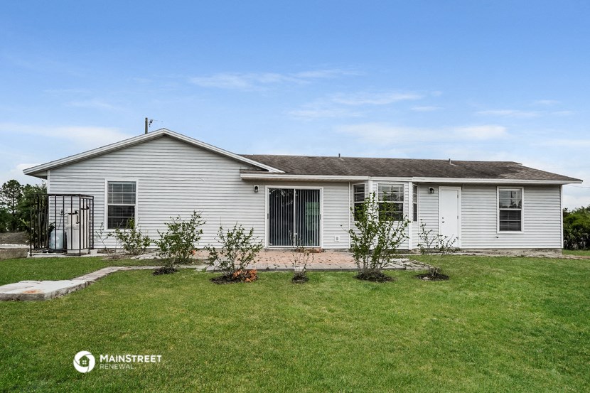a white house with a lawn and trees in front of it
