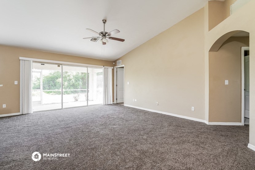 an empty living room with carpet and a ceiling fan