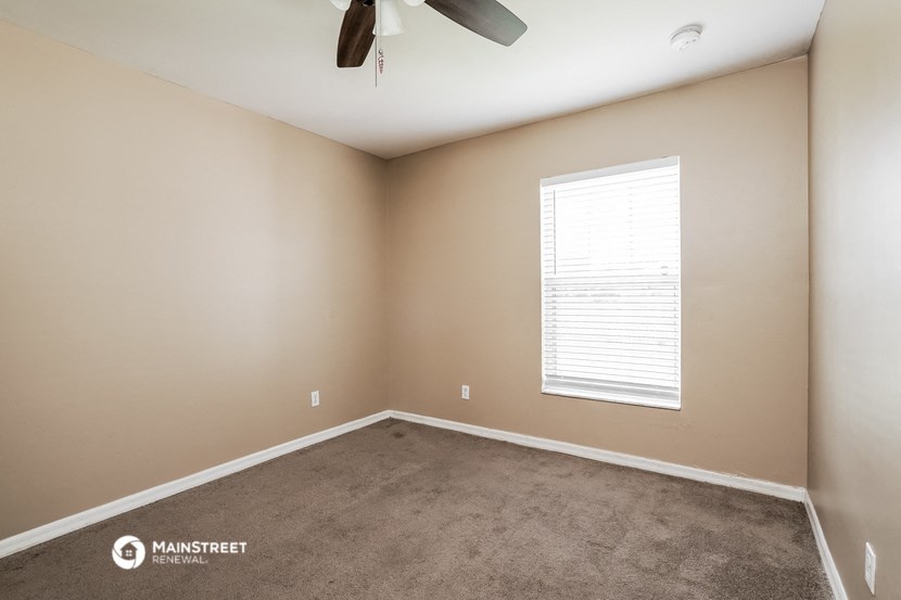 a carpeted room with a window and a ceiling fan