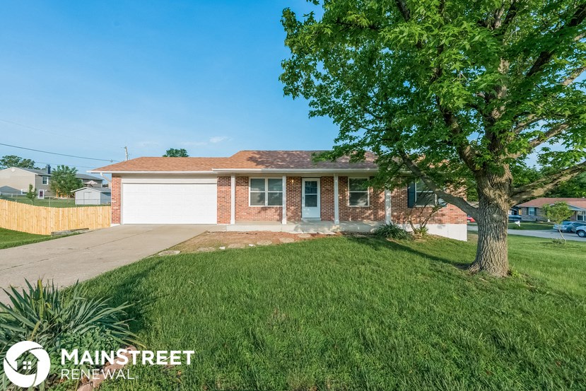 a small brick house with a tree in front of it