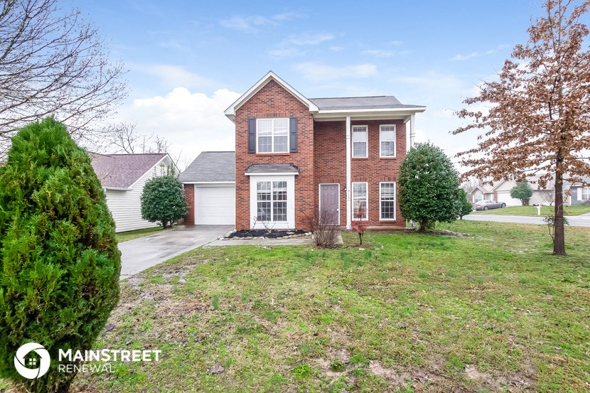 the front of a brick house with a yard and a driveway