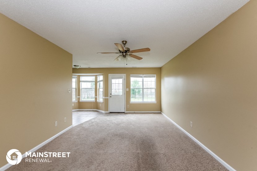 an empty living room with a ceiling fan