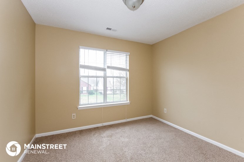 a bedroom with a large window and a carpeted floor