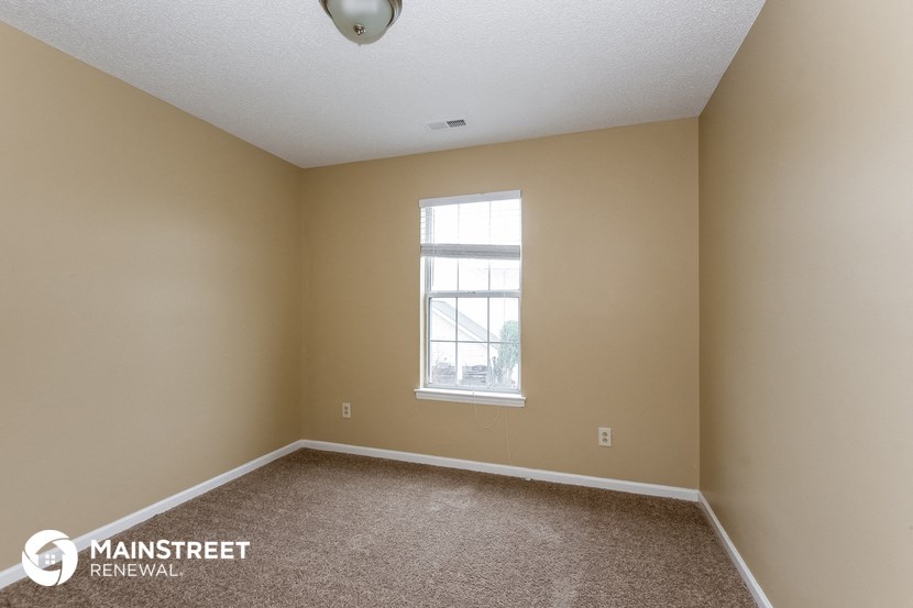 an empty room with a window and carpet