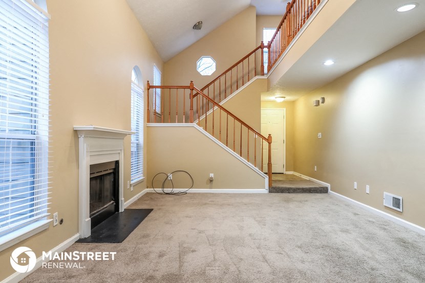 an empty living room with a fireplace and a staircase