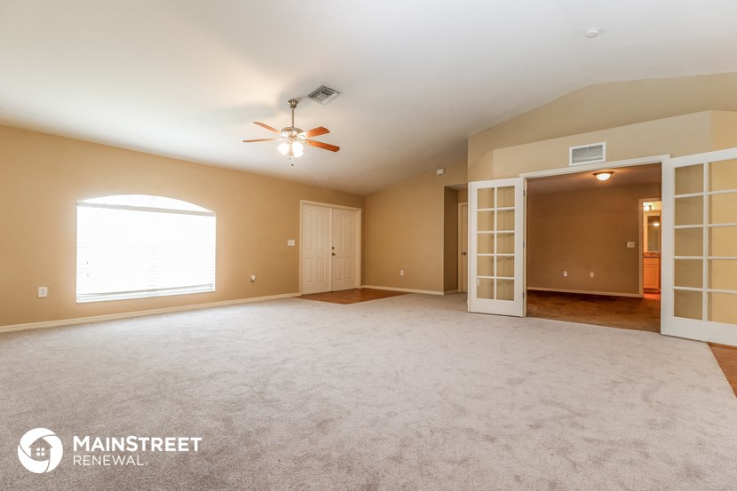 an empty living room with a ceiling fan and a window