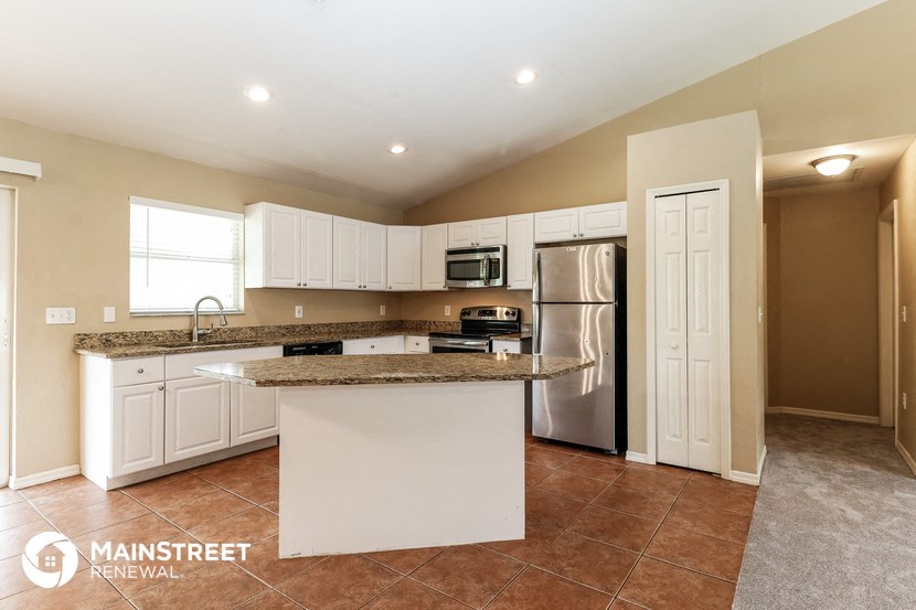 the kitchen has granite counter tops and white cabinets and stainless steel appliances