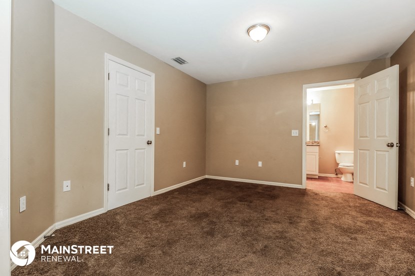 a bedroom with a carpeted floor and a door to a bathroom