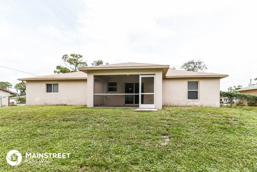 a small tan house with a grassy yard