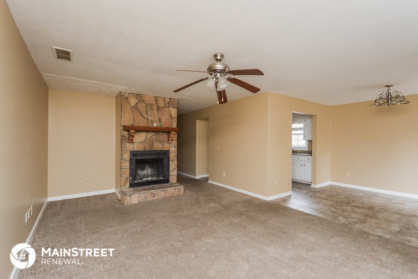 a living room with a fireplace and a ceiling fan