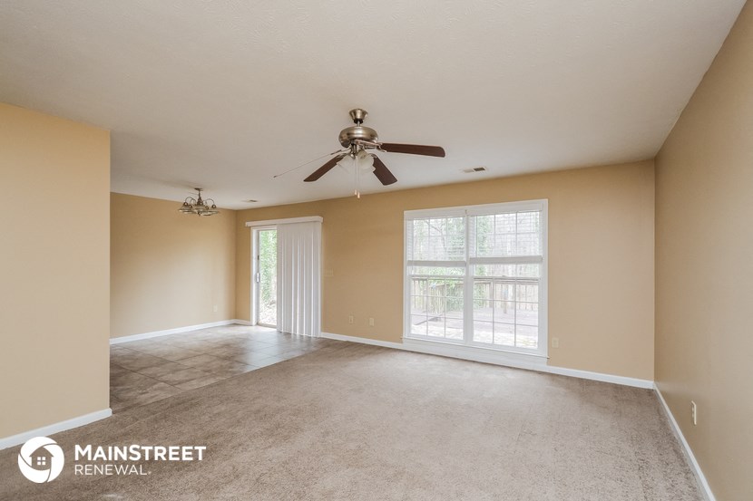 the living room of an empty house with a ceiling fan