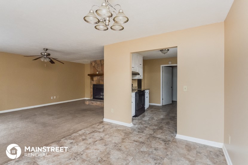 an empty living room and kitchen with a ceiling fan