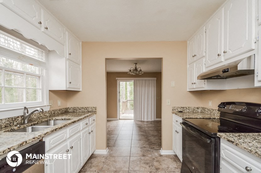 a kitchen with white cabinets and granite counter tops and a black stove and refrigerator