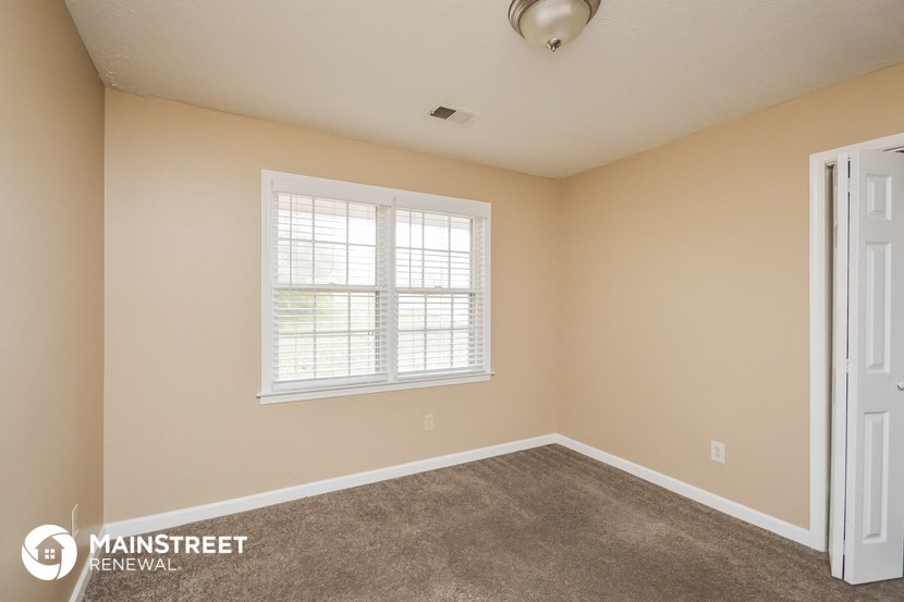 the spacious living room with carpeted flooring and a window