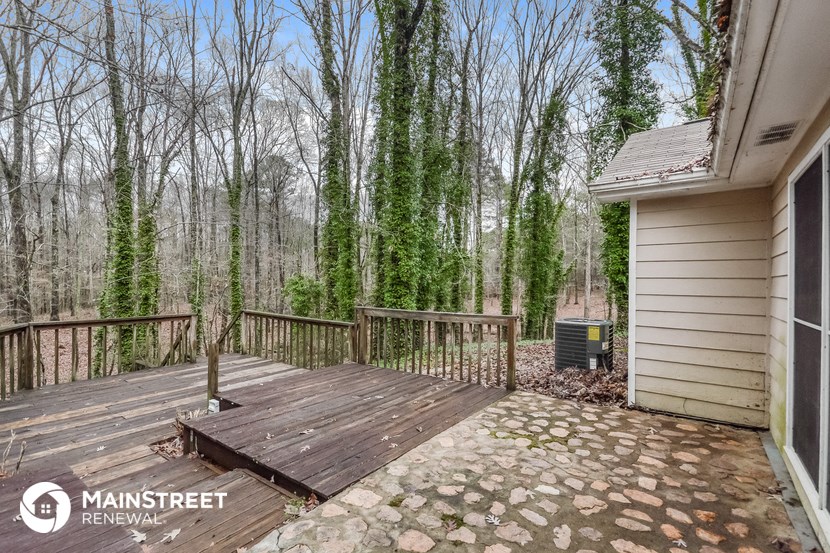 a deck with a house and trees in the background