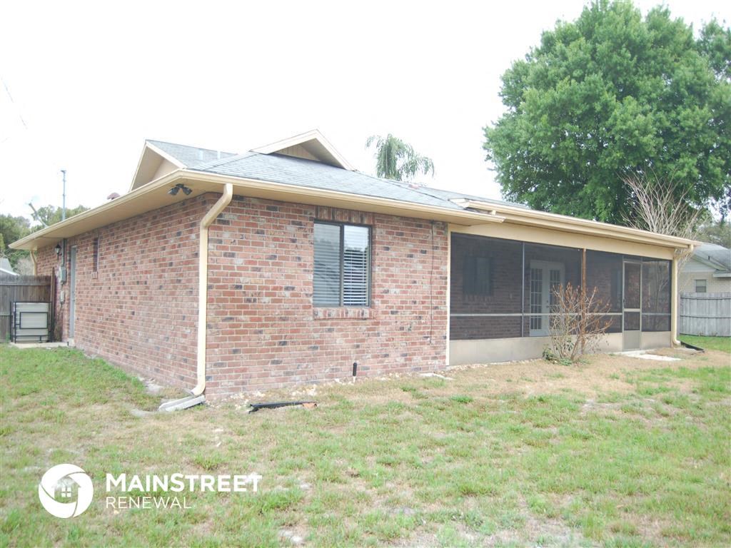the front of a brick house with a yard and a tree