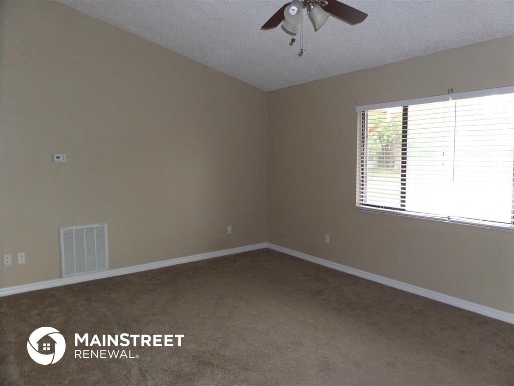 an empty room with a ceiling fan and a window