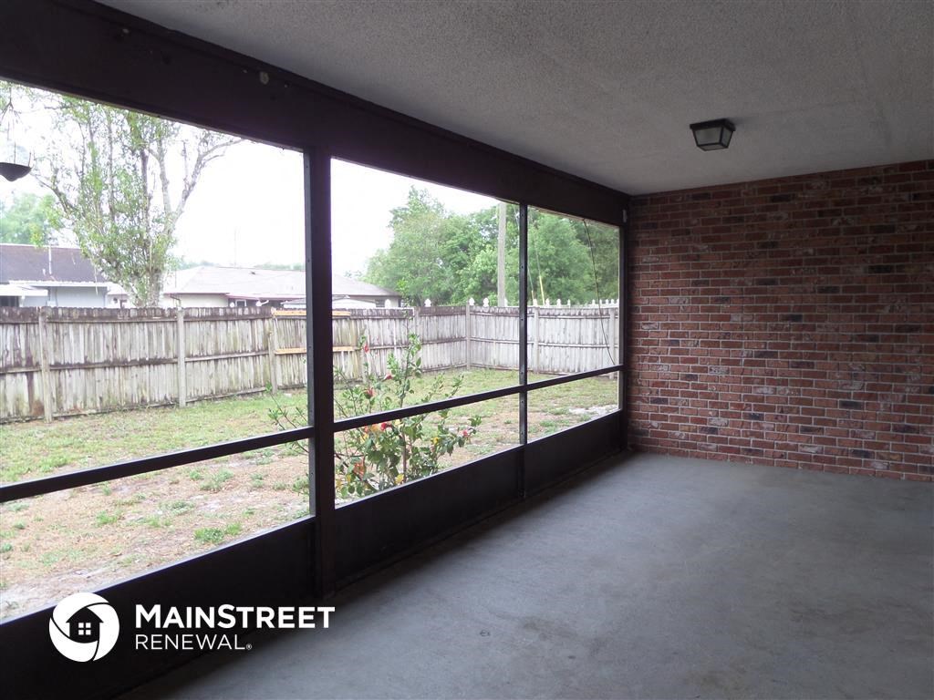 an empty living room with a brick wall and large window