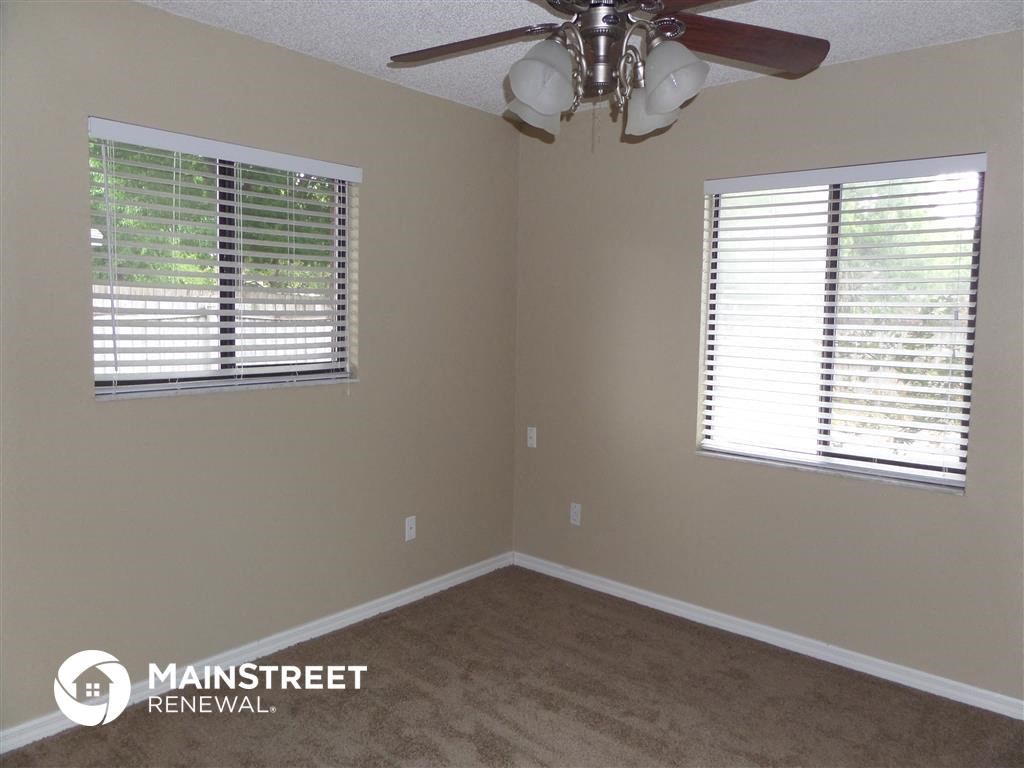 a bedroom with a ceiling fan and two windows