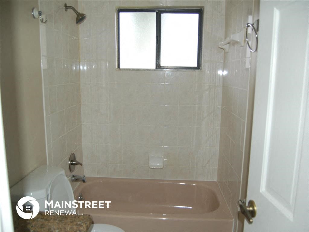 a bathroom with a tub and a toilet and a window