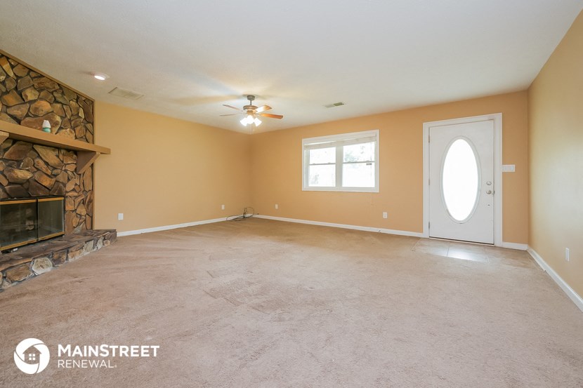 an empty living room with a fireplace and a ceiling fan