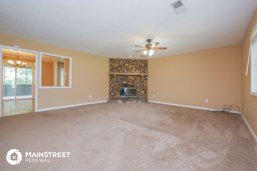 an empty living room with a fireplace and a ceiling fan